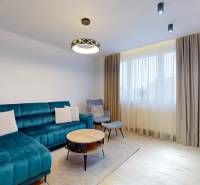 PREDAJ, 3 izbový dizajnový byt na Lidickom námestí, Košice - Furča - Obývačka v 3-izbovom byte s modrou pohovkou a podlahou s dreveným dekorom.