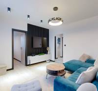 PREDAJ, 3 izbový dizajnový byt na Lidickom námestí, Košice - Furča - Obývacia izba v 3-izbovom byte s pohovkou, televízorom a podlahou s dreveným dekorom.