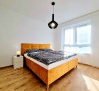 REZERVOVANÉ I Posledný investičný krásny 2-izbový byt | 62 m² | - Spálňa v 2-izbovom byte s posteľou, nočným stolíkom a podlahou s dreveným dekorom.
