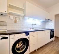Príjemný a priestranný 3-izbový byt | 83 m² |  - Kuchyňa v 3-izbovom byte s bielymi skrinkami a podlahou s dreveným dekorom.
