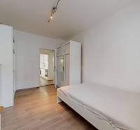 Príjemný a priestranný 3-izbový byt | 83 m² |  - Svetlá izba s posteľou, skriňou a podlahou s dreveným dekorom v 3-izbovom byte.