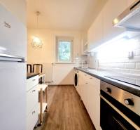 Príjemný a priestranný 3-izbový byt | 83 m² |  - Kuchyňa v 3-izbovom byte, biele skrinky, podlaha s dreveným dekorom.