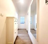 Príjemný a priestranný 3-izbový byt | 83 m² |  - Chodba v 3-izbovom byte s podlahou s dreveným dekorom a zrkadlom na stene.