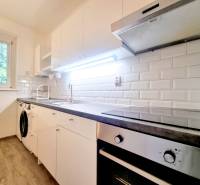 Príjemný a priestranný 3-izbový byt | 83 m² |  - Kuchyňa v 3-izbovom byte s bielymi skrinkami a podlahou s dreveným dekorom.