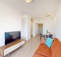 Nový, ešte neobývaný 1,5-izbový byt, parkovanie, Metropolis, Bottova - Obývačka s oranžovou sedačkou, jedálenským stolom a podlahou s dreveným dekorom v 2-izbovom byte.