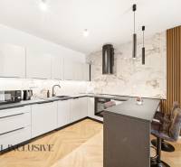 Na prenájom 2-izb. byt s terasou, Dun. Streda -Florida - Kuchyňa s bielymi skriňami, ostrovčekom a podlahou s dreveným dekorom v 4-izbovom byte.