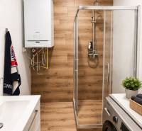Moderný 2-izbový byt v centre Kežmarku na predaj - Kúpeľňa v 2-izbovom byte s podlahou s dreveným dekorom a sprchovacím kútom.