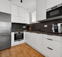 Predaj 2-izbový byt GREEN VILLAGE, 51m2, loggia, Dunajská Lužná - Kuchyňa v 2-izbovom byte s podlahou s dreveným dekorom, biele skrinky, spotrebiče.