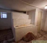 Pôvodný päťizbový rodinný dom s hospodárskymi budovami blízko centra o - Interiér rodinného domu so starou pecou, oknom a svetlom na strope.