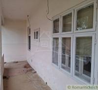 Pôvodný päťizbový rodinný dom s hospodárskymi budovami blízko centra o - Rodinný dom v Mužli s priechodnou terasou, oknami so žalúziami a betónovou podlahou.