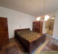 Pôvodný päťizbový rodinný dom s hospodárskymi budovami blízko centra o - Spálňa v rodinnom dome s drevenými skrinkami a podlahou s dreveným dekorom.