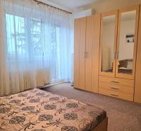 PRENÁJOM - Priestranný 3 izbový byt - Nitra, Centrum - Spálňa s veľkým oknom, záclonami a drevenou skriňou v 3-izbovom byte.