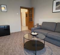 PRENÁJOM - Priestranný 3 izbový byt - Nitra, Centrum - Obývacia izba v 3-izbovom byte so sivou sedačkou a preskleným stolom.