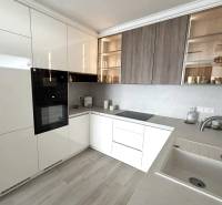 2 izbový A.3.1.- 58,91 m2 Bell Residence  - Kuchyňa v 2-izbovom byte s bielymi skrinkami a podlahou s dreveným dekorom.