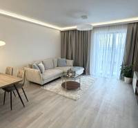 2 izbový A.3.1.- 58,91 m2 Bell Residence  - Obývacia izba v 2-izbovom byte s podlahou s dreveným dekorom, pohovkou a jedálenským stolom.