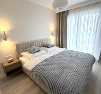 2 izbový A.3.1.- 58,91 m2 Bell Residence  - Spálňa v 2-izbovom byte s podlahou s dreveným dekorom, posteľou a závesmi.