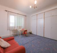 Na predaj rodinný dom Trnava, Zelenečská ulica, pozemok 1085 m2 - Rodinný dom obsahuje obývačku s kobercovou podlahou, oranžový gauč a biely stôl.