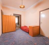 Na predaj rodinný dom Trnava, Zelenečská ulica, pozemok 1085 m2 - Izba v rodinnom dome s modrým kobercom, dreveným nábytkom a posteľou.