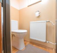 Na predaj rodinný dom Trnava, Zelenečská ulica, pozemok 1085 m2 - Toaleta v rodinnom dome s radiátorom a podlahou s dreveným dekorom.