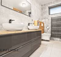 ALL INCLUSIVE I PERFEKTNÝ 4- IZBOVÝ RD SMART HOME - MOSTOVÁ (GA) - Kúpeľňa v rodinnom dome, šedé obklady, dve umývadlá, sprchový kút, drevený dekor.