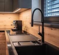 ALL INCLUSIVE I  4- IZBOVÝ RD SMART HOME NOVOSTAVBA- MOSTOVÁ (GA) - Kuchyňa v rodinnom dome s dreveným dekorom, čiernym drezom a moderným kávovarom.