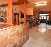  Podnikateľská príležitosť v obci Búč . - Interiér gastro priestoru so stolíkom a regálmi na knihy.