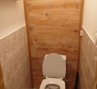 Na predaj 2i byt Levice - Toaleta so stenami obloženými dlažbou a dverami s dreveným dekorom v 2-izbovom byte.