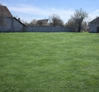 Na predaj výnimočný átriový rodinný dom s dvojgarážou v obci Dolná Seč - Záhrada v Dolnej Seči obklopená rodinnými domami a oplotením pod modrou oblohou.