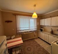 Rodinný dom Martin - Valča - Kuchyňa v rodinnom dome s bielymi skrinkami, vzorovaným kobercom a jedálenským stolom.