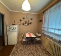 Rodinný dom Martin - Valča - Kuchyňa v rodinnom dome s chladničkou, stolom a dekoračnými predmetmi na stene.