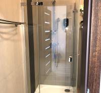Na predaj apartmán s veľkou terasou Podhájská. - Sprchovací kút so sklenenou zástenou v garsónke s jemnými béžovými obkladačkami.