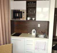 Na predaj veľký 49m2 apartmán Podhájská.  - Kompaktný kuchynský kút v 2-izbovom byte s bielymi skrinkami a spotrebičmi.