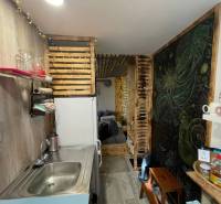 Bývanie v prírode, na dosah mesta, murov. chatka s celoročným využitím - Kuchynský kút s drevenými dekoráciami a poličkami, podlaha s dreveným dekorom.