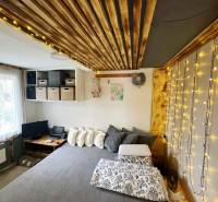 Bývanie v prírode, na dosah mesta, murov. chatka s celoročným využitím - Interiér rodinného domu so svetelnými reťazami, podlahou s dreveným dekorom a pohodlnou posteľou.