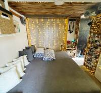 Bývanie v prírode, na dosah mesta, murov. chatka s celoročným využitím - Interiér rodinného domu s posteľou, vankúšmi a svetelnou dekoráciou.