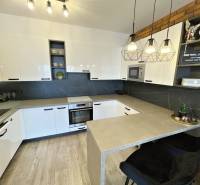 KOŠICE-2 IZBOVÝ BYT,NOVOSTAVBA,KOMPLET ZARIADENÝ,VL.PARK. MIESTO - Kuchyňa v 2-izbovom byte s bielymi skrinkami a podlahou s dreveným dekorom.