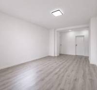 NOVÁ KOMPLET. REK., 3–IZB. BYT, PIVNICA, BALKÓN, DUKELSKÁ, BERNOLÁKOVO - Priestranná izba v 3-izbovom byte s podlahou s dreveným dekorom a bielymi stenami.