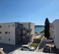 CHORVÁTSKO - Apartmány 40 m od mora vo výstavbe - SRIMA, VODICE - Budovy blízko mora v meste Srima, s výhľadom na pobrežie a automobilmi na parkovisku.