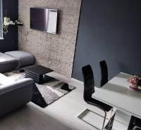 Na prenájom pekný 3izbový byt po rekonštrukcii 800,- Eur - Obývacia izba s televízorom, gaučom, čiernymi stoličkami a podlahou s dreveným dekorom.