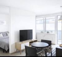 Na predaj 1,5 izbový apartmán v BA III Malokrasňanská 42,34m2 - Svetlá obývacia izba v 2-izbovom byte s televízorom a jedálenským stolom.