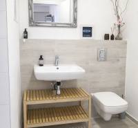 Na predaj 1,5 izbový apartmán v BA III Malokrasňanská 42,34m2 - Kúpeľňa s umývadlom a zrkadlom, jednoduchá dekorácia a svetlé obklady stien v 2-izbovom byte.