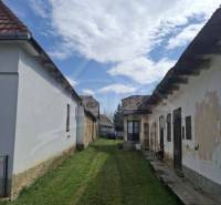 Vymeňte mestský hluk za ticho Bystričky: Domček s dušou a potenciálom - Ozdín: Starší rodinný dom so záhradou a oblačným nebom.