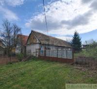 Vymeňte mestský hluk za ticho Bystričky: Domček s dušou a potenciálom - Rodinný dom v Ozdíne, obklopený záhradou a stromami, pod modrou oblohou.