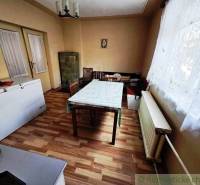 Rodinný dom s 2 bytovými jednotkami, veľkým pozemkom a hospodárskym zá - Jedáleň v rodinnom dome s podlahou s dreveným dekorom a kachľovou pecou.