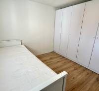 Na predaj 2 izbový murovaný domček, Bratislava, Záhorská Bystrica - Spálňa s posteľou, bielou skriňou a podlahou s dreveným dekorom v 2-izbovom byte.