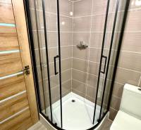 Na predaj 2 izbový murovaný domček, Bratislava, Záhorská Bystrica - Kúpeľňa v 2-izbovom byte s rohovým sprchovacím kútom a podlahou s dreveným dekorom.
