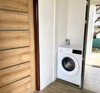 Na predaj 2 izbový murovaný domček, Bratislava, Záhorská Bystrica - Dvere s dreveným dekorom a práčka v 2-izbovom byte.