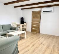 Na predaj 2 izbový murovaný domček, Bratislava, Záhorská Bystrica - Obývacia izba v rodinnom dome s drevenými trámami a podlahou s dreveným dekorom.