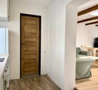 Na predaj 2 izbový murovaný domček, Bratislava, Záhorská Bystrica - Kuchyňa v 2-izbovom byte s podlahou s dreveným dekorom a drevenými trámami na strope.