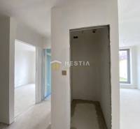 Posledný byt!! NA PREDAJ novostavba, 3-izb.byt, Petrova Ves - Interiér nedokončeného 2-izbového bytu s omietnutými stenami a veľkým oknom.